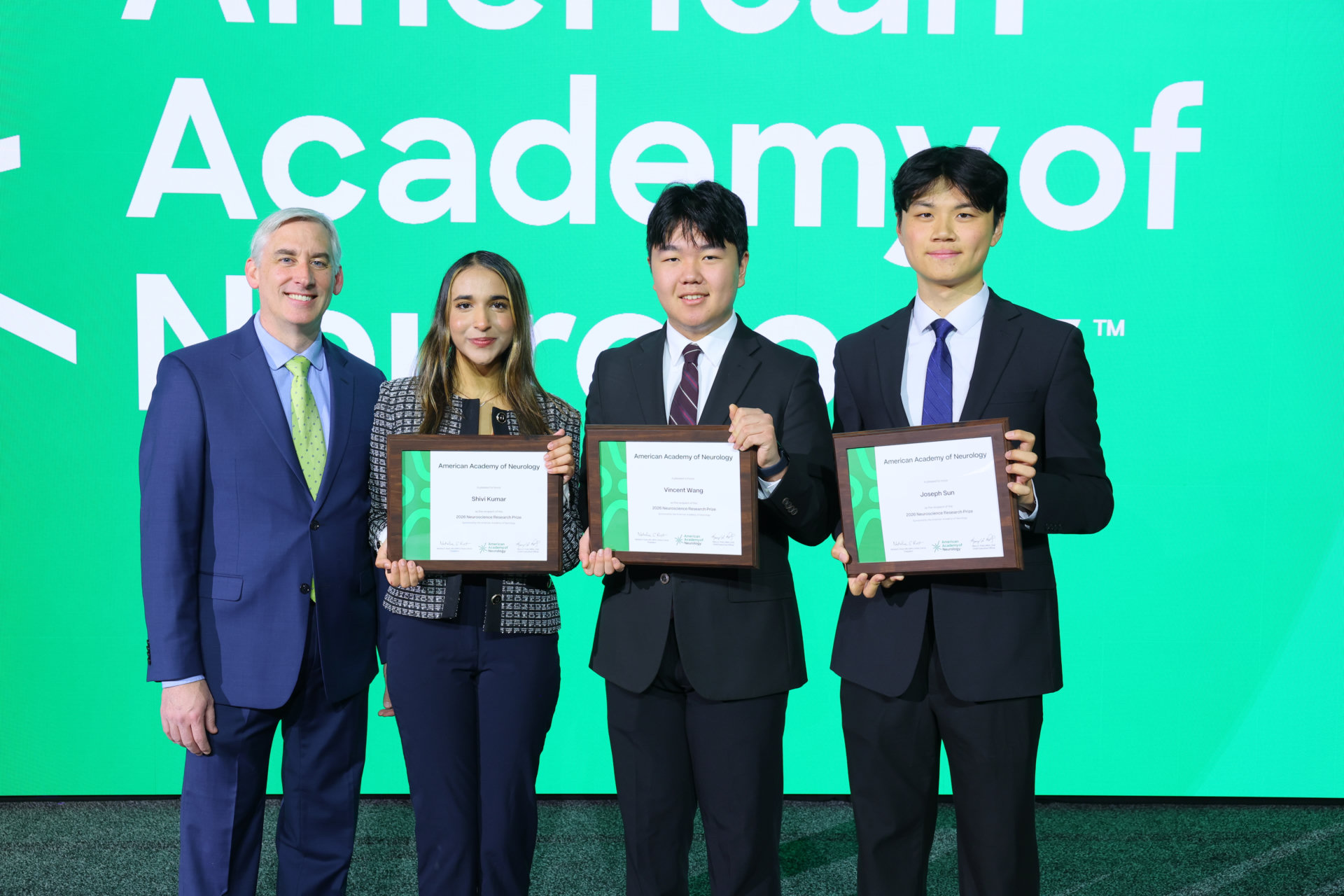 Joseph Sun holding his AAN Neuroscience Research Prize onstage with fellow award recipients
